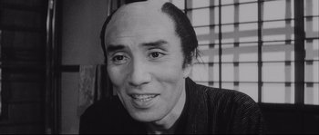 Movie still from “The Sword of Doom” (1966), directed by Kihachi Okamoto – An older man with a bald head is smiling for the camera; Close Up shot, Low angle