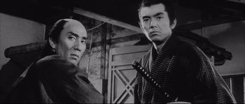 Movie still from “The Sword of Doom” (1966), directed by Kihachi Okamoto – A black - and - white photo of two people holding a sword; Close Up shot, Low angle