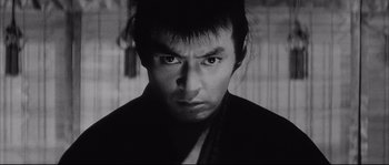 Movie still from “The Sword of Doom” (1966), directed by Kihachi Okamoto – A black and white photo of a man with a serious look on his face; Close Up shot, Low angle
