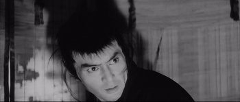 Movie still from “The Sword of Doom” (1966), directed by Kihachi Okamoto – A black and white photo of a man with a strange look on his face; Close Up shot, Low angle