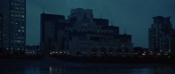 Movie still from “The Tailor of Panama” (2001), directed by John Boorman – A large building that is lit up at night; Extreme Wide shot, Low angle