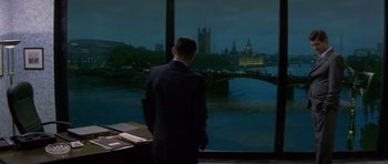 Movie still from “The Tailor of Panama” (2001), directed by John Boorman – A man standing in front of a window at night; Wide shot, Over the shoulder angle