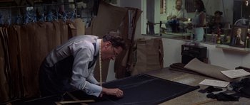 Movie still from “The Tailor of Panama” (2001), directed by John Boorman – A man in a room with a large piece of black fabric; Medium shot, High angle