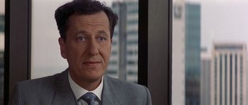 Movie still from “The Tailor of Panama” (2001), directed by John Boorman – A person wearing a suit and tie; Close Up shot, Over the shoulder angle