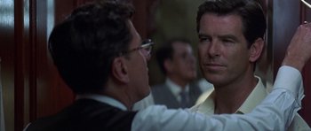 Movie still from “The Tailor of Panama” (2001), directed by John Boorman – Two men are talking to each other in front of other men; Close Up shot, Over the shoulder angle