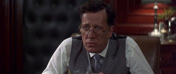 Movie still from “The Tailor of Panama” (2001), directed by John Boorman – A person wearing glasses and a tie; Close Up shot, Over the shoulder angle