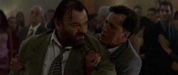 Movie still from “The Tailor of Panama” (2001), directed by John Boorman – Two men in suits and ties are holding each other; Close Up shot, Low angle