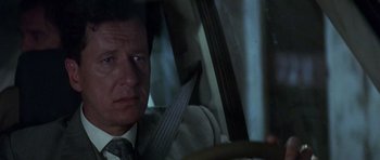 Movie still from “The Tailor of Panama” (2001), directed by John Boorman – A person sitting in a car holding a steering wheel; Close Up shot, Over the shoulder angle