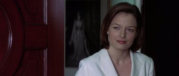 Movie still from “The Tailor of Panama” (2001), directed by John Boorman – A woman standing in front of a painting of a woman; Close Up shot, Over the shoulder angle