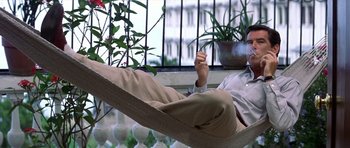 Movie still from “The Tailor of Panama” (2001), directed by John Boorman – A man sitting in a hammock with his feet on the ground; Medium shot, Low angle