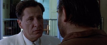 Movie still from “The Tailor of Panama” (2001), directed by John Boorman – A man in a suit and tie talking to another man in a suit and tie; Close Up shot, Over the shoulder angle