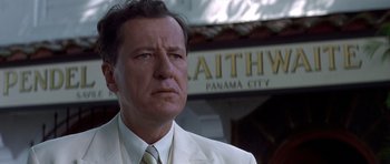 Movie still from “The Tailor of Panama” (2001), directed by John Boorman – A man in a white suit standing in front of a building; Close Up shot, Low angle