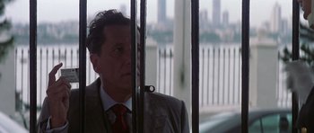 Movie still from “The Tailor of Panama” (2001), directed by John Boorman – A man wearing a suit and tie standing in front of a fence; Close Up shot, Low angle