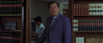 Movie still from “The Tailor of Panama” (2001), directed by John Boorman – A man in a suit and tie standing in front of a mirror; Medium shot, Over the shoulder angle