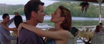 Movie still from “The Tailor of Panama” (2001), directed by John Boorman – A man and a woman embracing each other in front of a body of water; Medium shot, Over the shoulder angle