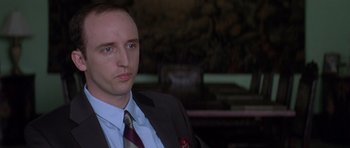 Movie still from “The Tailor of Panama” (2001), directed by John Boorman – A person wearing a suit and tie; Close Up shot, Over the shoulder angle