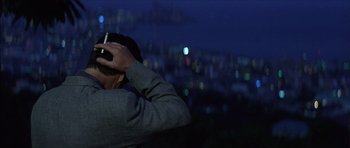 Movie still from “The Tailor of Panama” (2001), directed by John Boorman – A man holding a cell phone up to his head; Close Up shot, Over the shoulder angle