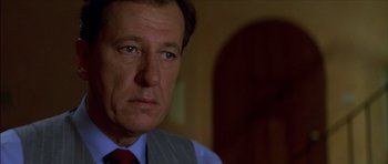 Movie still from “The Tailor of Panama” (2001), directed by John Boorman – A person wearing a suit and tie; Close Up shot, Low angle