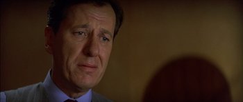 Movie still from “The Tailor of Panama” (2001), directed by John Boorman – A person wearing a suit and tie; Close Up shot, Over the shoulder angle