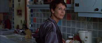 Movie still from “The Tailor of Panama” (2001), directed by John Boorman – A woman standing in front of a kitchen counter; Close Up shot, Over the shoulder angle