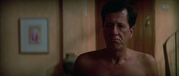 Movie still from “The Tailor of Panama” (2001), directed by John Boorman – A man with no shirt is sitting in a bathroom; Close Up shot, Low angle
