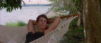 Movie still from “The Tailor of Panama” (2001), directed by John Boorman – A woman laying in a hammock near a body of water; Medium shot, Low angle