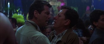Movie still from “The Tailor of Panama” (2001), directed by John Boorman – A couple of men standing next to each other; Close Up shot, Over the shoulder angle