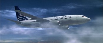 Movie still from “The Tailor of Panama” (2001), directed by John Boorman – An airplane flying through the air on a cloudy day; Extreme Wide shot, Low angle