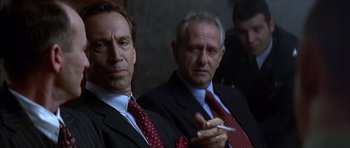 Movie still from “The Tailor of Panama” (2001), directed by John Boorman – A couple of men in suits sitting next to each other; Close Up shot, Over the shoulder angle