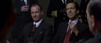 Movie still from “The Tailor of Panama” (2001), directed by John Boorman – A couple of men sitting next to each other in suits; Close Up shot, Low angle