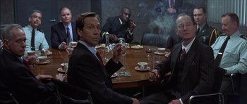 Movie still from “The Tailor of Panama” (2001), directed by John Boorman – A group of people sitting around a table; Medium shot, Over the shoulder angle