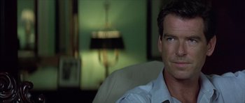 Movie still from “The Tailor of Panama” (2001), directed by John Boorman – A person sitting in a chair wearing a tie; Close Up shot, Over the shoulder angle