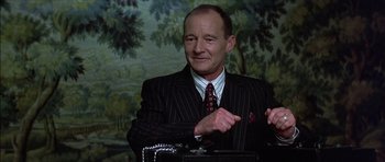 Movie still from “The Tailor of Panama” (2001), directed by John Boorman – An older man in a suit and a tie; Medium shot, Low angle