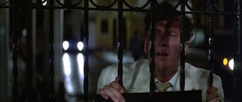 Movie still from “The Tailor of Panama” (2001), directed by John Boorman – A man in white shirt and yellow tie behind bars; Close Up shot, Low angle