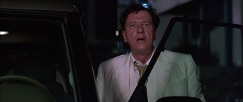 Movie still from “The Tailor of Panama” (2001), directed by John Boorman – A man in a white suit holding a rifle; Close Up shot, Low angle