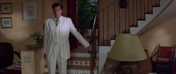 Movie still from “The Tailor of Panama” (2001), directed by John Boorman – A man in a white suit standing in front of a staircase; Medium shot, Low angle