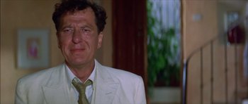 Movie still from “The Tailor of Panama” (2001), directed by John Boorman – A person wearing a suit and tie; Close Up shot, Over the shoulder angle