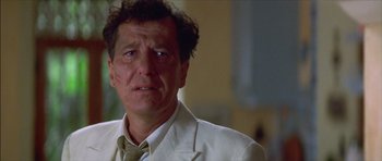 Movie still from “The Tailor of Panama” (2001), directed by John Boorman – A person wearing a suit and tie; Close Up shot, Low angle