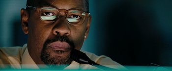 Movie still from “The Taking of Pelham 123” (2009), directed by Tony Scott – A person wearing glasses and holding a microphone; Close Up shot, Low angle