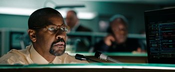 Movie still from “The Taking of Pelham 123” (2009), directed by Tony Scott – A man sitting at a microphone in front of another man; Close Up shot, Low angle