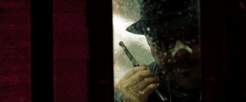 Movie still from “The Taking of Pelham 123” (2009), directed by Tony Scott – A man in a hat is holding a stick in front of a window; Extreme Close Up shot, Low angle
