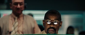 Movie still from “The Taking of Pelham 123” (2009), directed by Tony Scott – A person wearing glasses and a suit; Close Up shot, Low angle