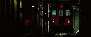 Movie still from “The Taking of Pelham 123” (2009), directed by Tony Scott – A red train traveling down train tracks at night; Extreme Wide shot, Low angle