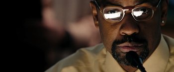 Movie still from “The Taking of Pelham 123” (2009), directed by Tony Scott – A person wearing glasses and a yellow shirt; Extreme Close Up shot, Over the shoulder angle