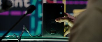 Movie still from “The Taking of Pelham 123” (2009), directed by Tony Scott – A person touching a speaker on top of a table; Extreme Close Up shot, Overhead angle