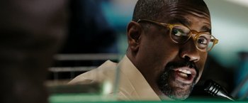 Movie still from “The Taking of Pelham 123” (2009), directed by Tony Scott – A person wearing a suit and glasses; Close Up shot, Over the shoulder angle