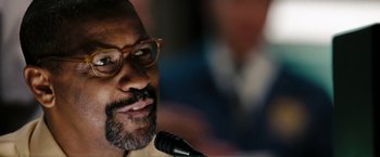 Movie still from “The Taking of Pelham 123” (2009), directed by Tony Scott – A person speaking into a microphone; Close Up shot, Over the shoulder angle