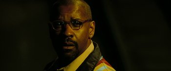 Movie still from “The Taking of Pelham 123” (2009), directed by Tony Scott – A person wearing glasses and a jacket; Close Up shot, Low angle