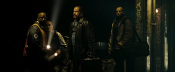 Movie still from “The Taking of Pelham 123” (2009), directed by Tony Scott – A group of men standing next to each other holding luggage; Medium shot, Low angle