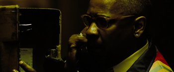 Movie still from “The Taking of Pelham 123” (2009), directed by Tony Scott – A man with glasses is talking on a phone; Extreme Close Up shot, Low angle